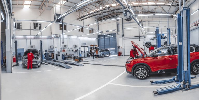 Service auto modern în care mecanicii lucrează la autoturisme, ilustrând un caz de finanțare pentru capital de lucru